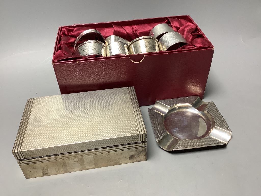 A presentation engine-turned silver cigarette box, a similar ashtray and a collection of silver napkin rings, Approximately 13.5oz weighable